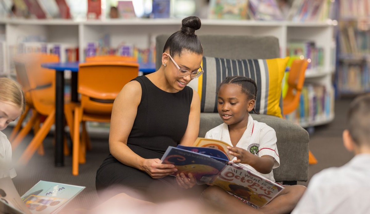 A teacher and a student reading a book.
