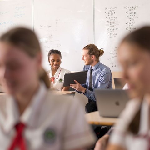 A student and teacher interacting in a classroom.